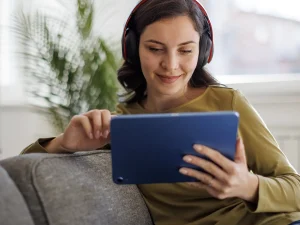 Woman sitting on a couch watching something on her tablet