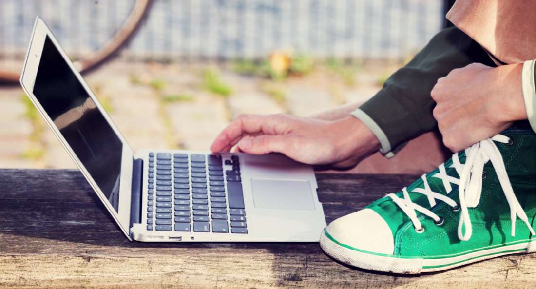 A person kneeling while using their laptop