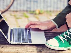 A person kneeling while using their laptop