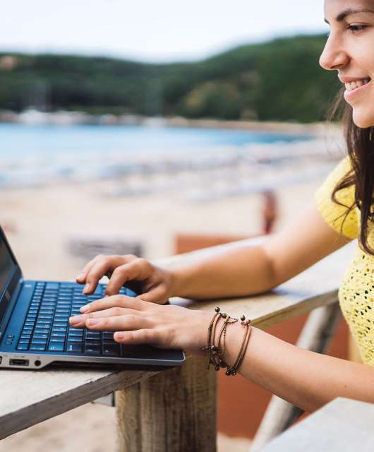 girl working on computer by a beach