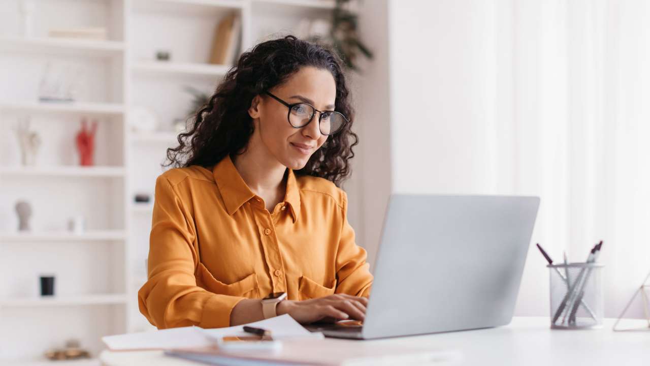 Woman sitting at a desk and typing on a laptop.