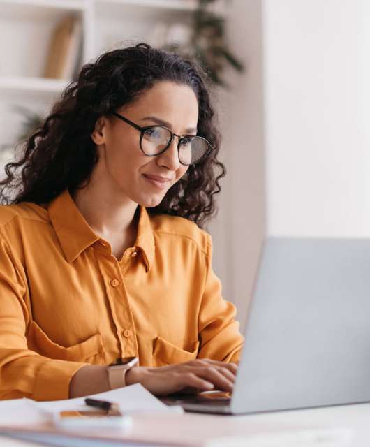 Woman sitting at a desk and typing on a laptop.