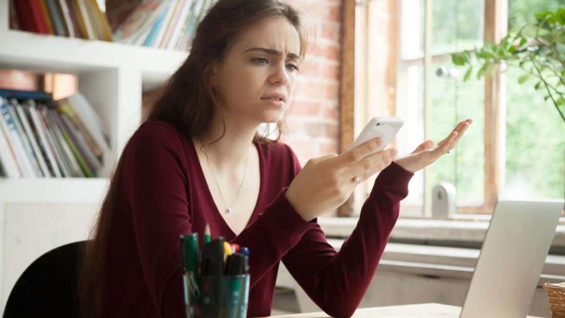 woman looking frustrated at phone