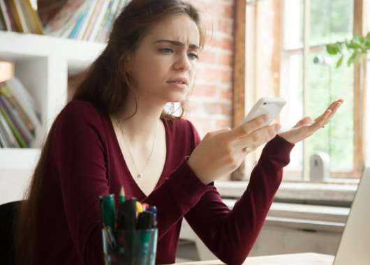 woman looking frustrated at phone