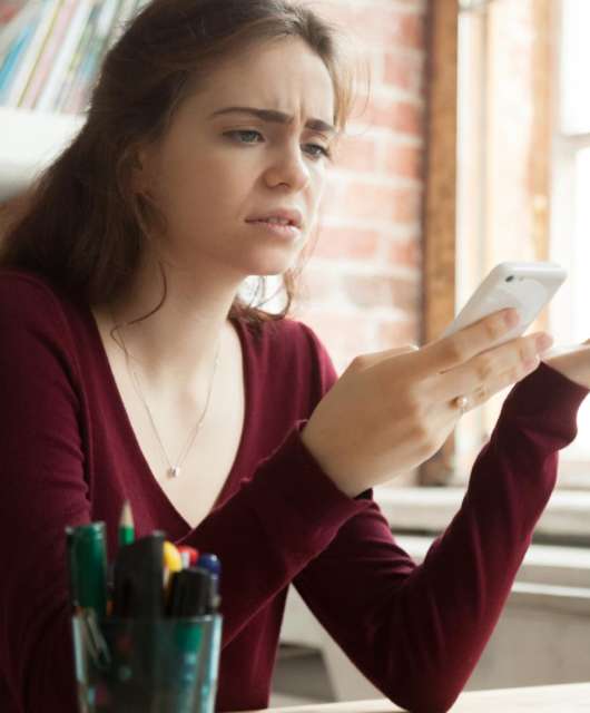 woman looking frustrated at phone
