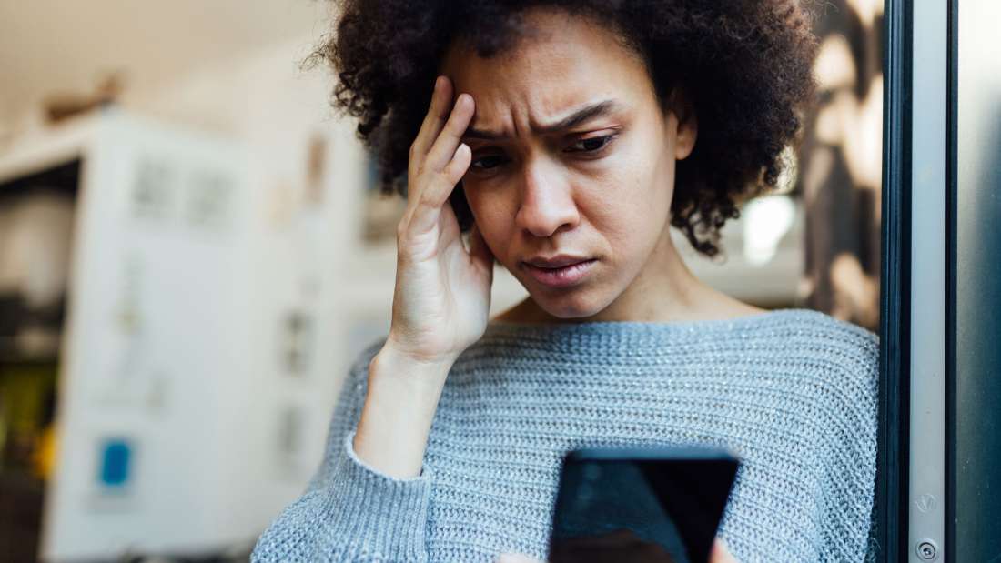 Image of a person looking at their phone with a worried expression
