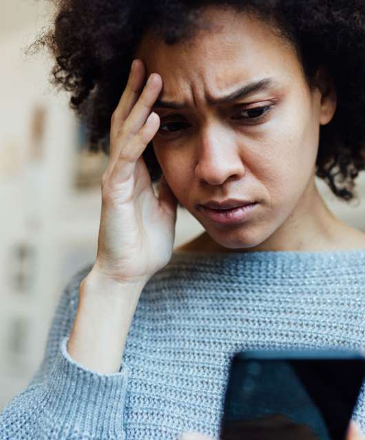 Image of a person looking at their phone with a worried expression