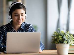 Young woman using a laptop with over-ear headphones