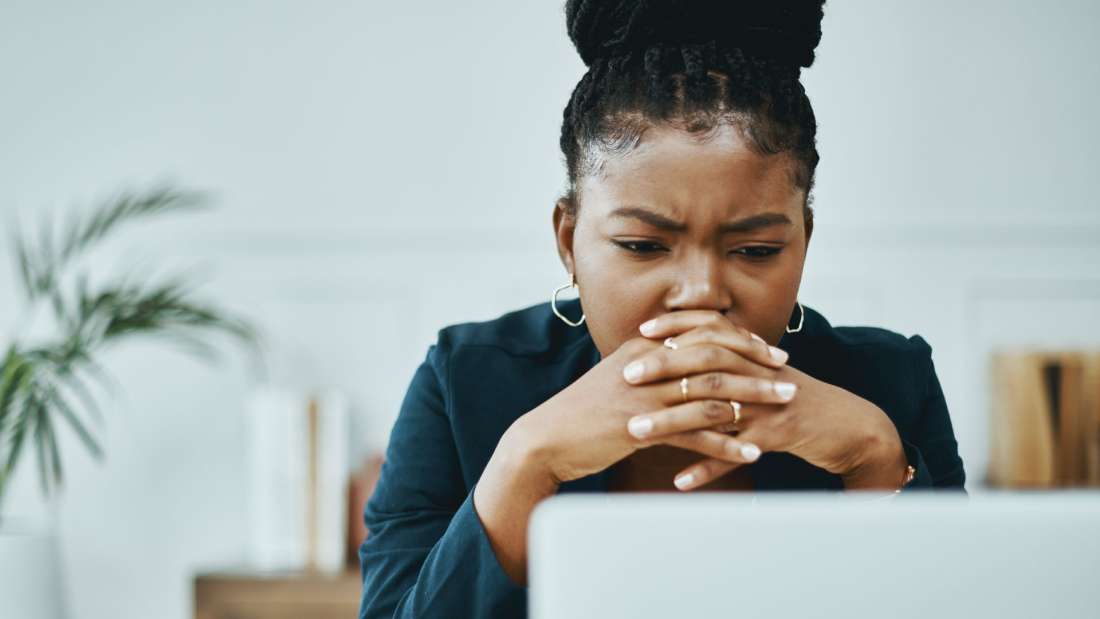 Woman with hands over mouth staring at a computer