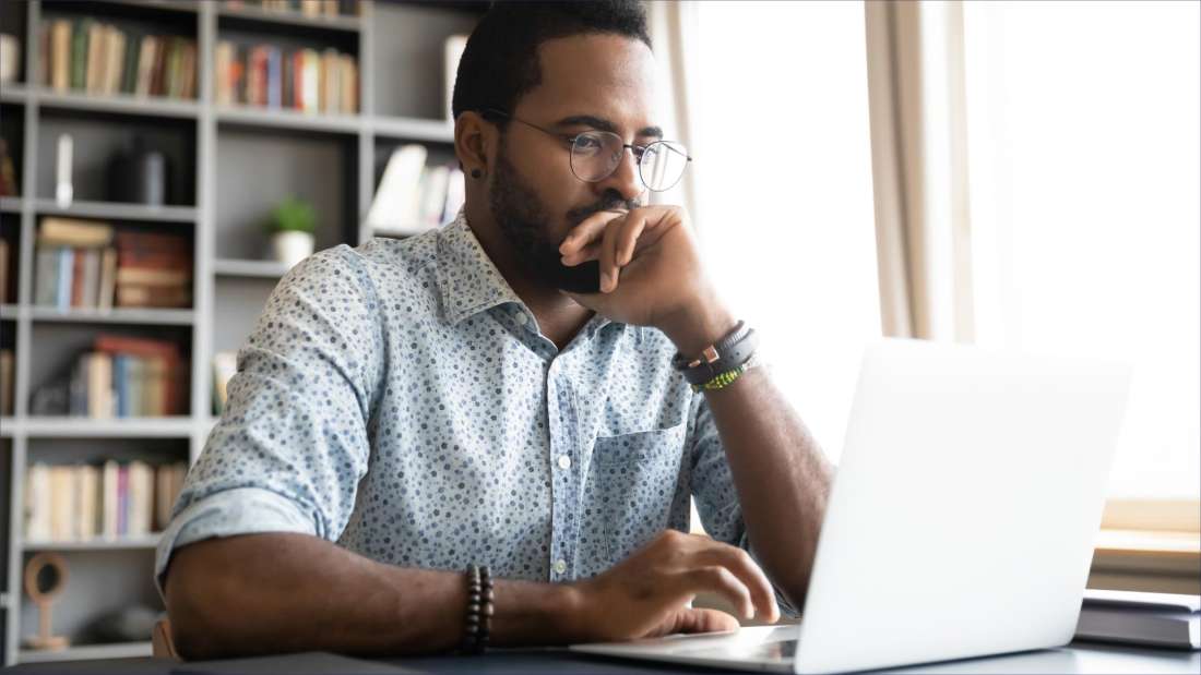 Man sitting and looking at a laptop.