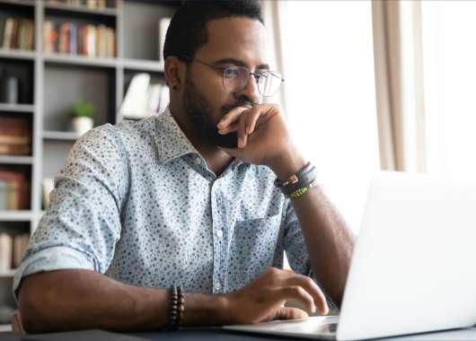Man sitting and looking at a laptop.