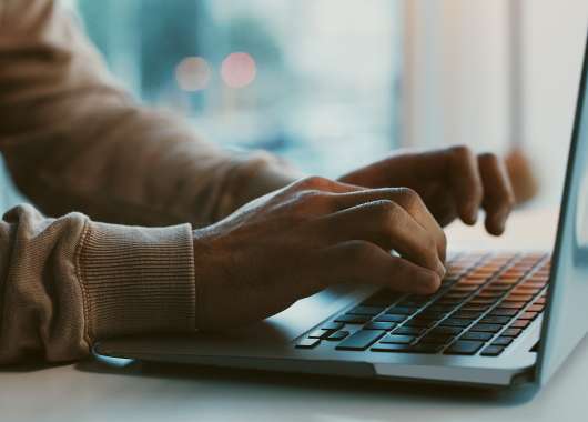 Two hands hovering over a laptop keyboard.