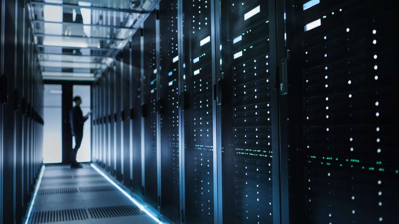 Person standing at the end of a hallway of computer servers.