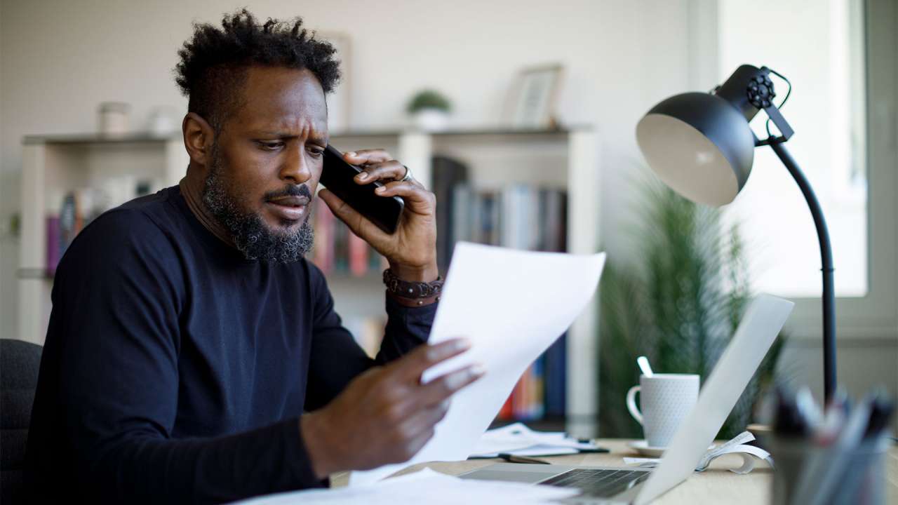 Worried man talking on the phone while working from home