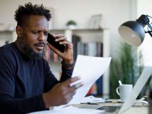 Worried man talking on the phone while working from home