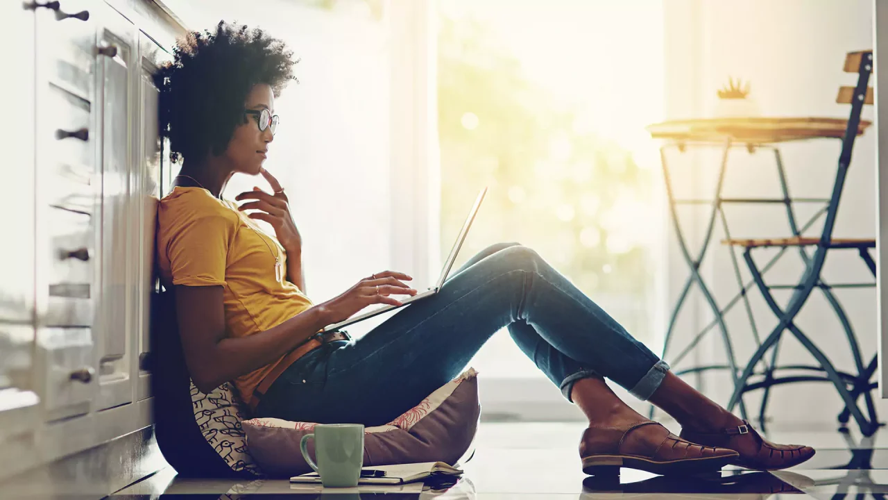 A woman sitting on the ground with a laptop.