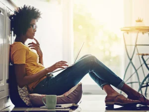 A woman sitting on the ground with a laptop.