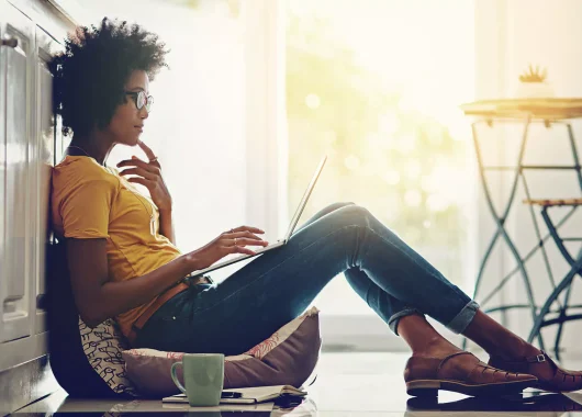 A woman sitting on the ground with a laptop.