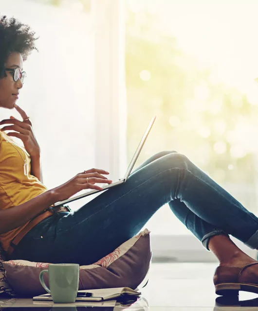 A woman sitting on the ground with a laptop.