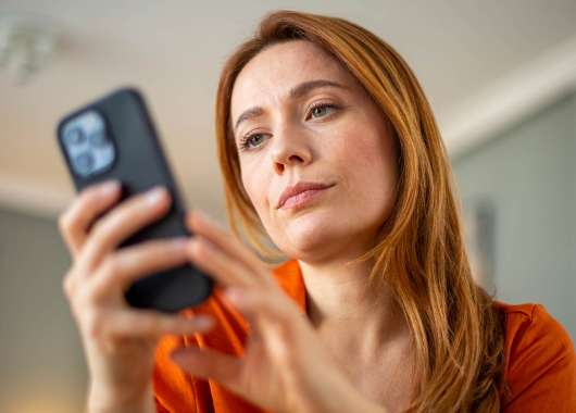 a woman looking at potential scam text messages on her cell phone