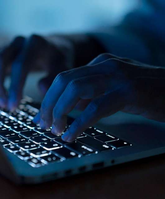 A figure of a dark web surfer using a laptop to access the dark web.