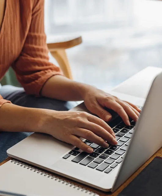 A young professional works on their laptop in a coffee shop.