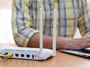 a cropped photo of a person in a plaid shirt changing their IP address on a laptop