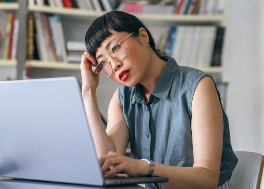 A stock photo of a woman using a laptop to browse websites.