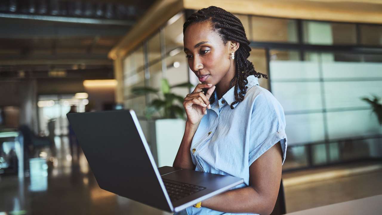 A woman in braids and a blue top checks how much RAM is on her laptop.