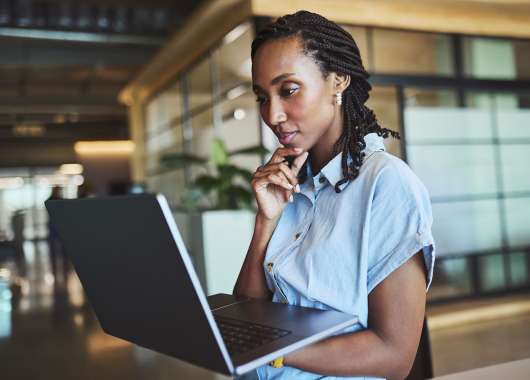 A woman in braids and a blue top checks how much RAM is on her laptop.