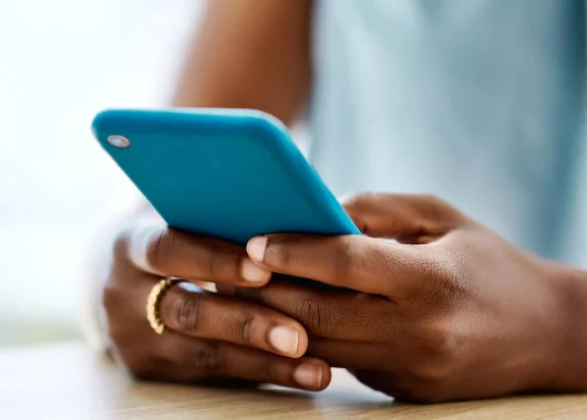 A cropped photo of a woman's hands holding a cell phone with a blue case.