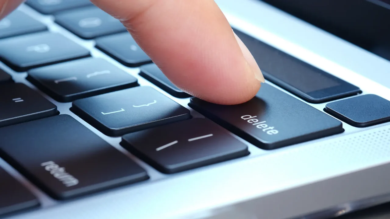 A photo of a finger pressing the delete button on a Mac keyboard.
