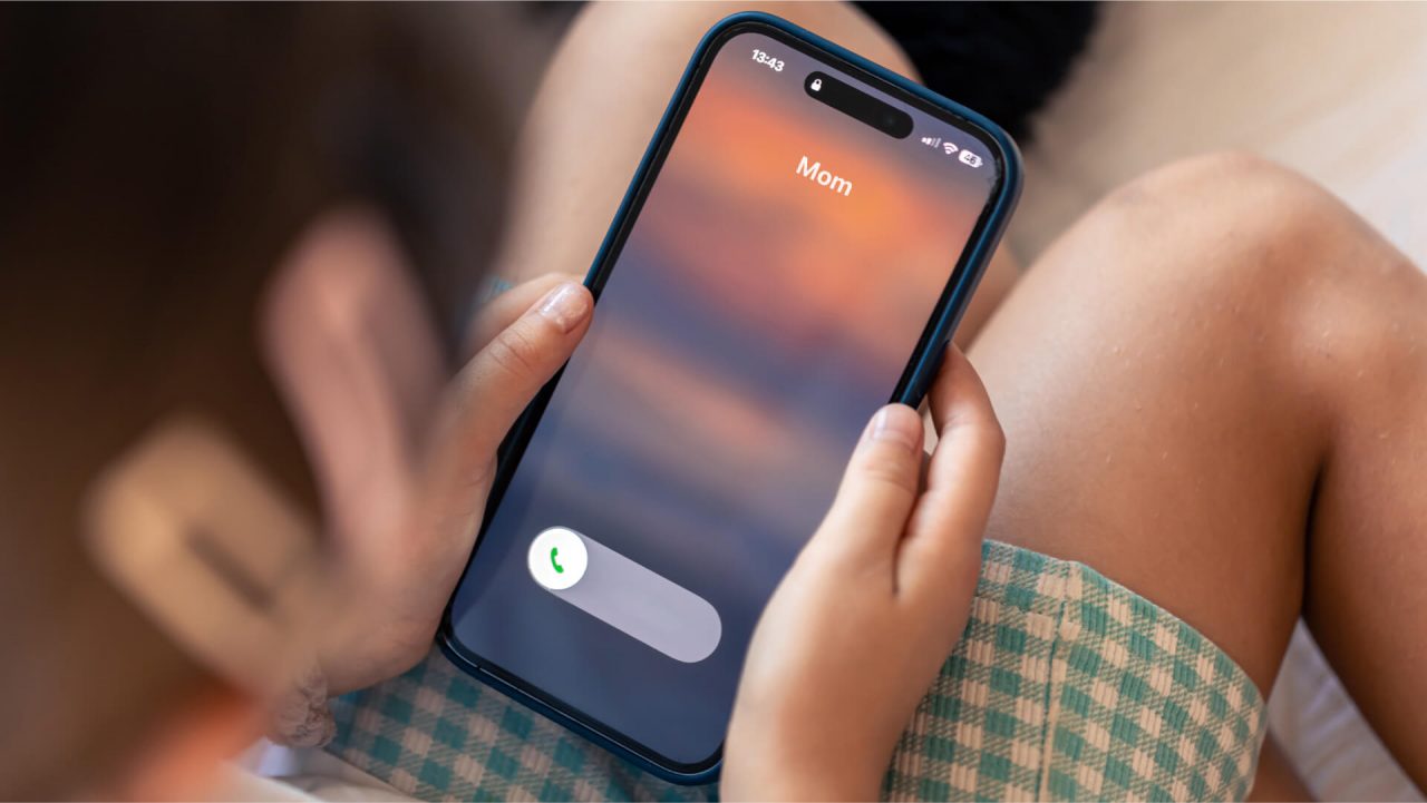 An image of a child receiving a call from their mom when it is actually a dark AI recreation that copies the mom’s voice.