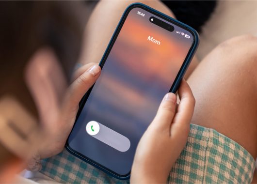 An image of a child receiving a call from their mom when it is actually a dark AI recreation that copies the mom’s voice.