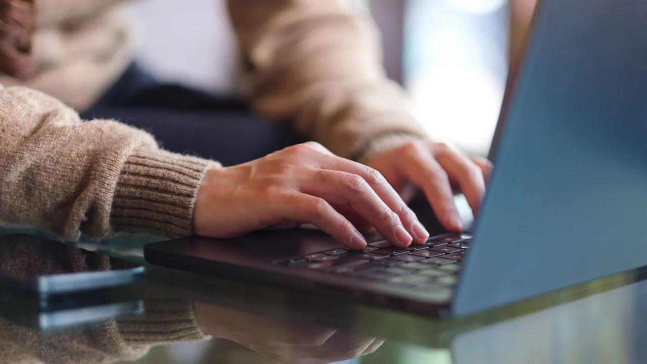 Close-up of a laptop, with a person's hands on the keyboard.
