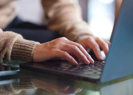 Close-up of a laptop, with a person's hands on the keyboard.