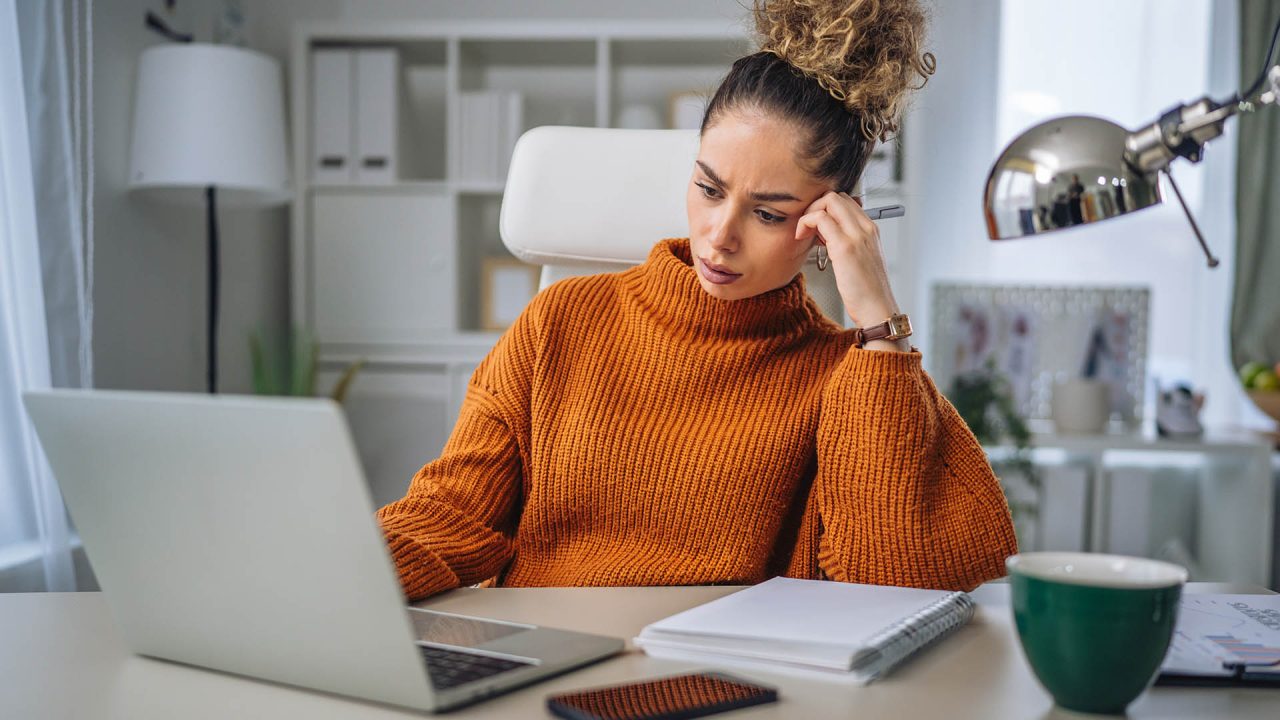 A woman wearing a sweater works on her desk.