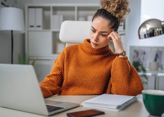 A woman wearing a sweater works on her desk.
